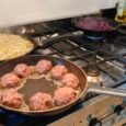 Drie pannen op het fornuis: acht gehaktballen, een grote rösti van aardappelreepjes en rode kool