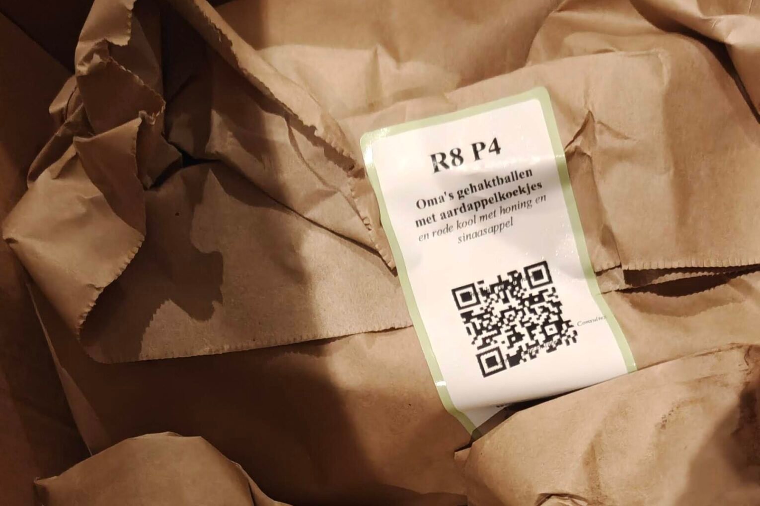 Papieren zakken in de Ekomenu doos, elk met een label van het recept en het aantal personen